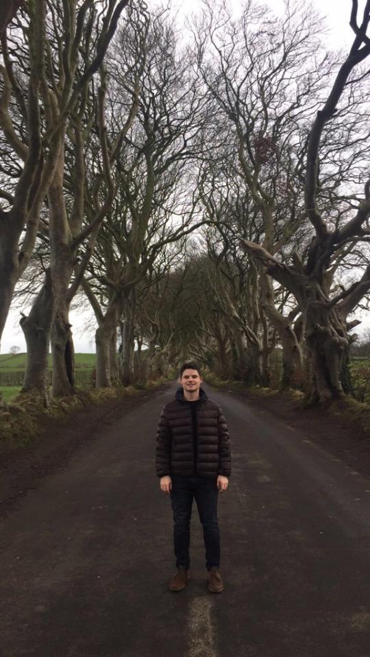 Joel standing on a tree-lined country road in Northern Ireland while travelling.